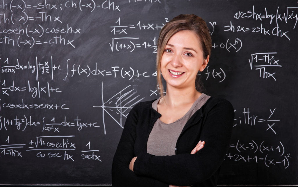 Maths Teacher in Front of Chalk Board full of Maths Equations